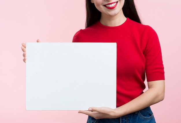 Foto gratuita donna del primo piano che tiene foglio di carta bianco