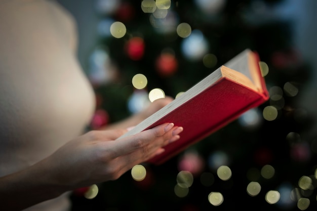 クリスマスの物語の本を保持しているクローズアップの女性