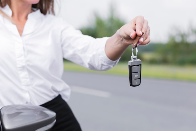 車のキーを保持しているクローズアップの女性