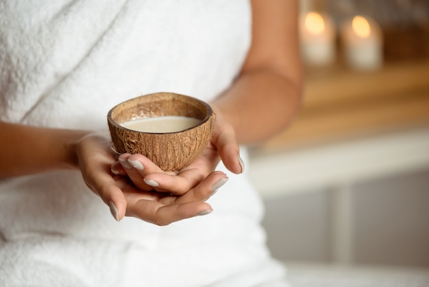 Close up of woman holding coconut in spa salon.