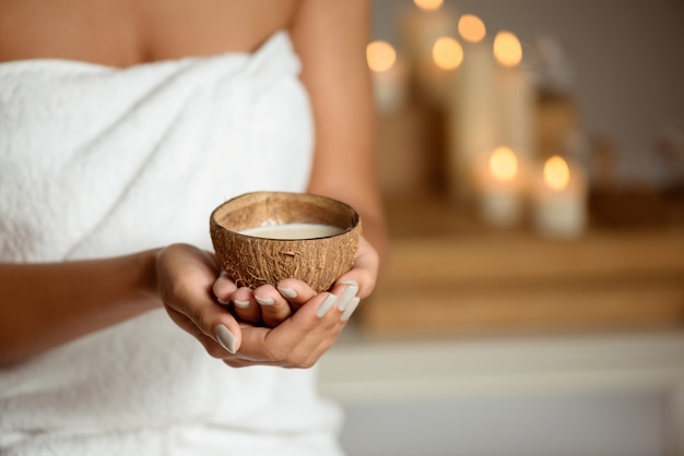 Close up of woman holding coconut in spa salon.