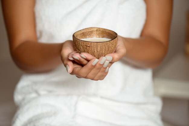 Close up of woman holding coconut in spa salon.