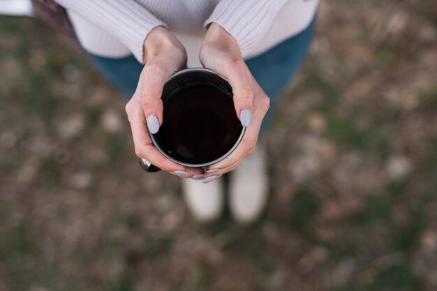 コーヒーを保持しているクローズアップの女性