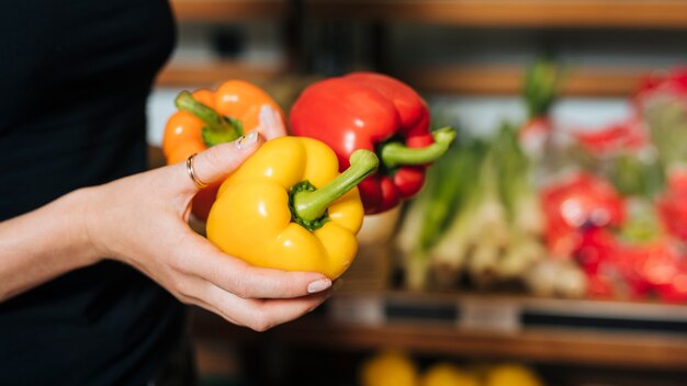 Close-up woman holding colourful bell peppers