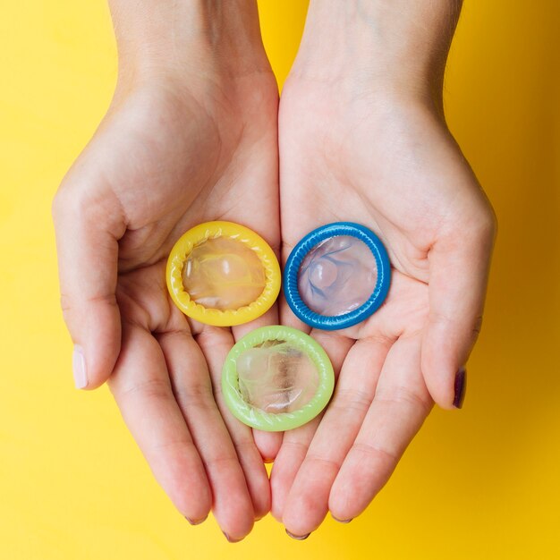 Close-up woman holding colourful condoms