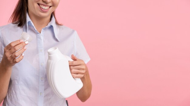 Close-up woman holding detergent laundry bottle