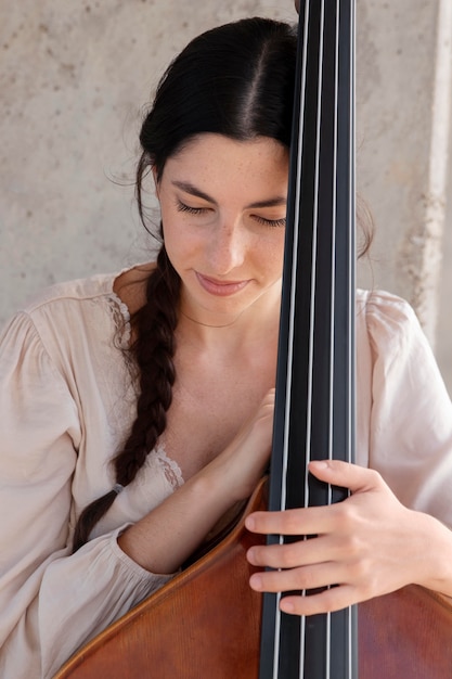 Free photo close up woman holding double bass