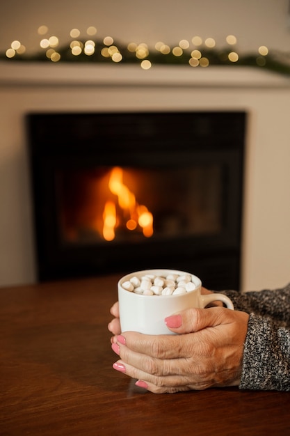 Free photo close-up woman holding drink near the fireplace