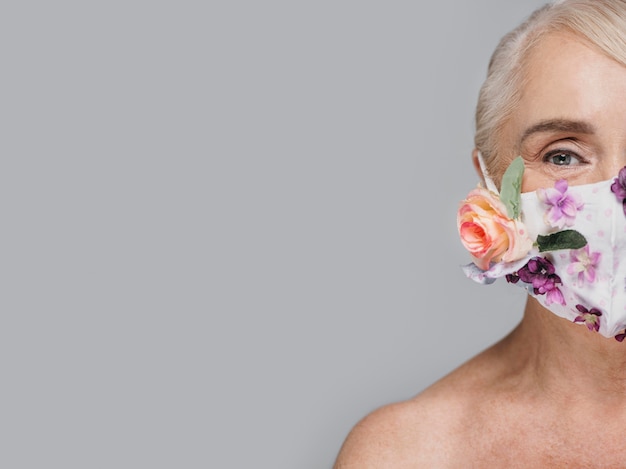 Close-up woman holding floral mask with copy-space