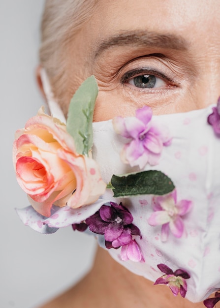 Foto gratuita donna del primo piano che tiene maschera floreale