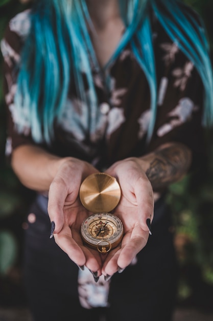 Крупным планом женщина, держащая золотой винтажный компас в руке