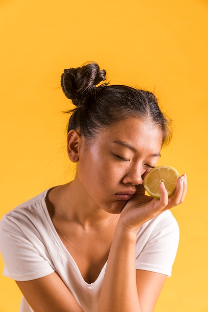 Foto gratuita donna del primo piano che tiene metà del limone