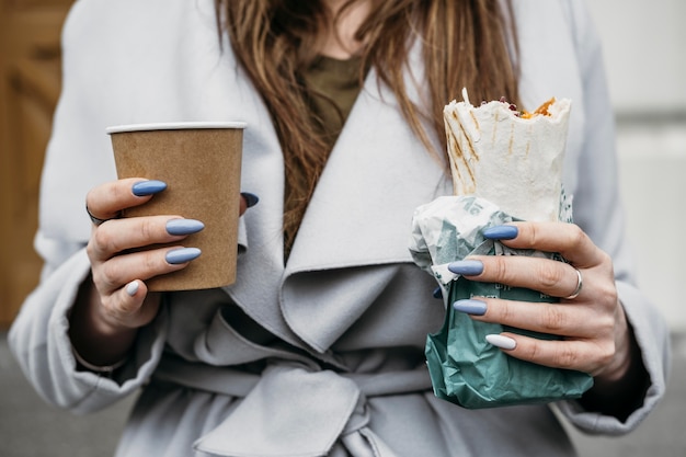 Donna del primo piano che tiene kebab e caffè