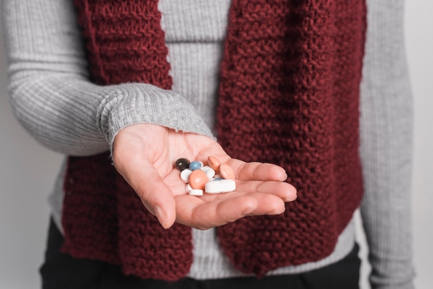 Close-up of woman holding many pills in hand