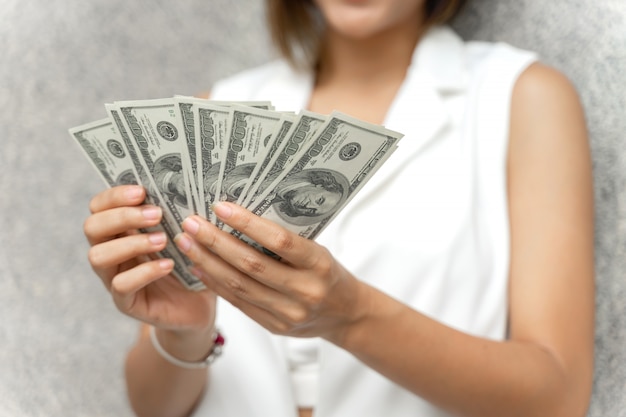 крупным планом женщина, держащая деньги долларовые банкноты в руке