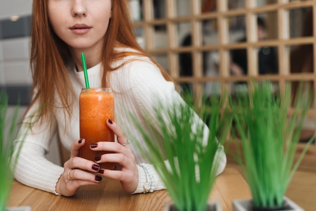 Foto gratuita primo piano della donna che tiene un bicchiere di frullato arancione