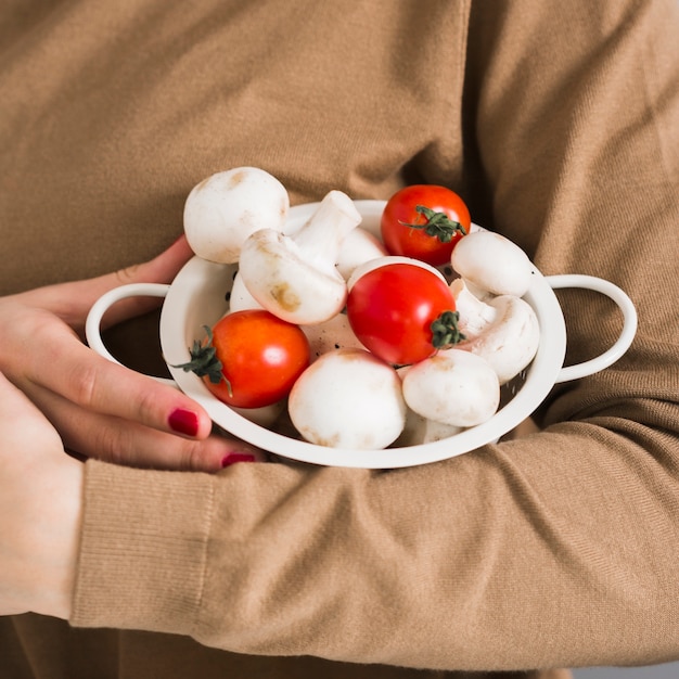 Женщина конца-вверх держа органические грибы и томаты