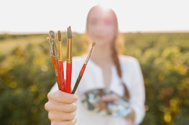 Close-up woman holding paintbrushes