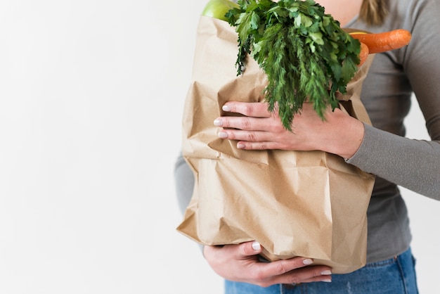 Close-up woman holding paper bag with vegetables
