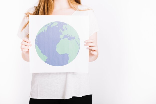 Close-up of woman holding paper with printed globe against white background