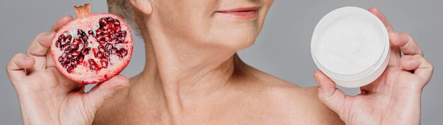 Close-up woman holding pomegranate and cream