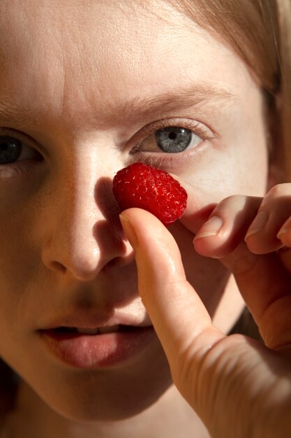 Close up woman holding raspberry