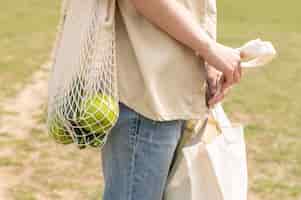 Free photo close-up woman holding reusable bags in nature