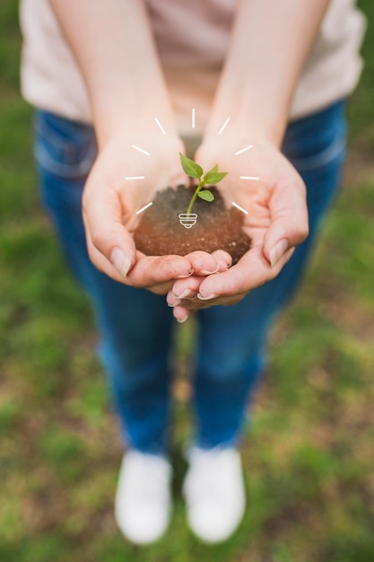 植物で土を保持している女性をクローズアップ