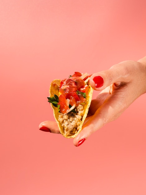 Close-up woman holding taco with red background