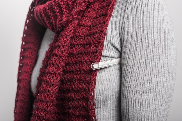 Close-up of woman holding thermometer under her arm