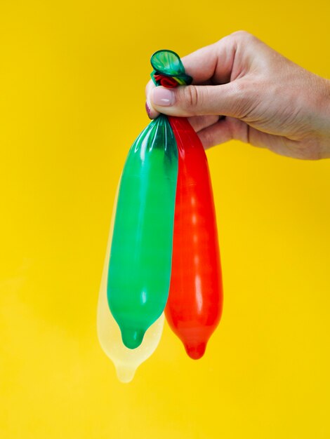 Close-up woman holding up colourful condoms