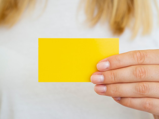 Close-up woman holding up yellow business card