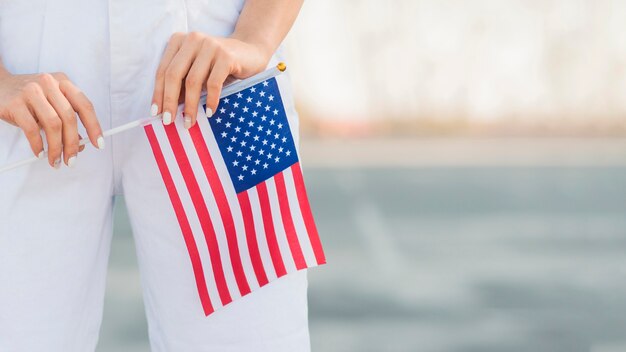 Крупным планом женщина держит в руках флаг США