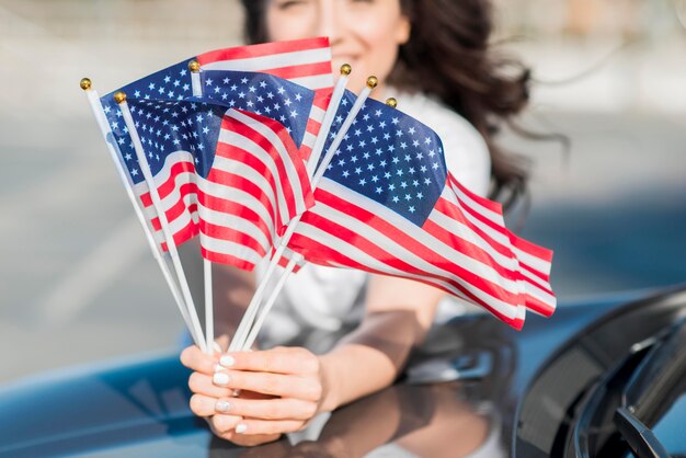 Женщина конца-вверх держа флаги США на автомобиле