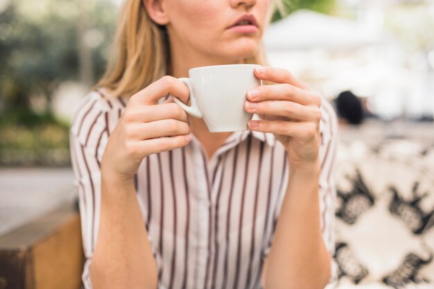 Close-up of woman holding white coffee cup in her hand