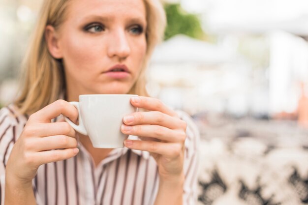 Close-up of woman holding white coffee cup