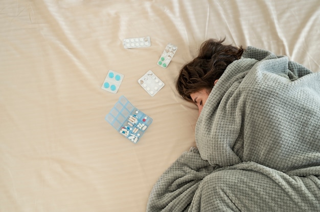 Бесплатное фото Крупным планом женщина в постели с таблетками