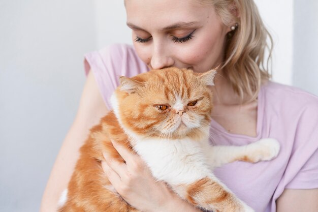 Close up woman kissing cat on head