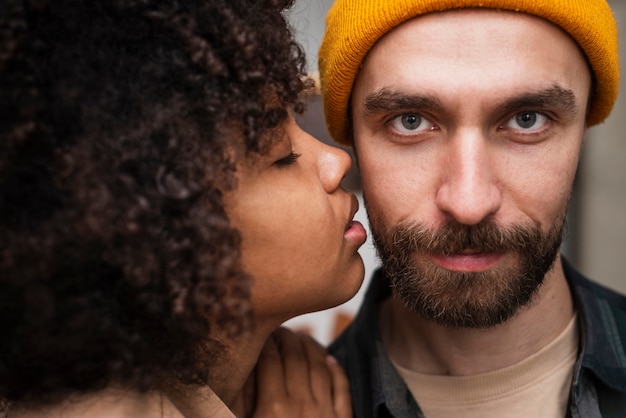 Close-up woman kissing hipster man