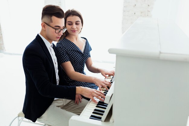 Крупный план женщины, смотрящей на красивого мужчину, играющего на пианино