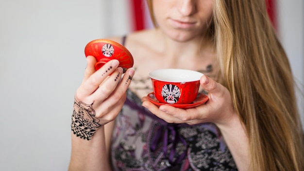 カップで伝統的に調製されたお茶を見ている女性のクローズアップ