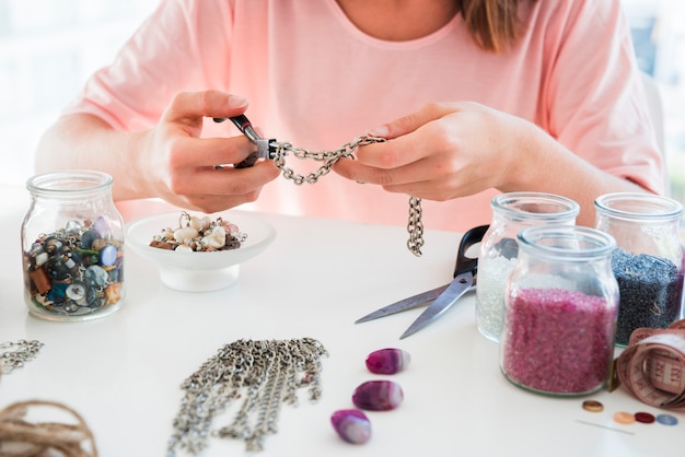 Free photo close-up of a woman making the handmade bracelet with chain and beads