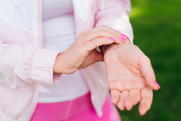 Close-up woman measuring her pulse outdoors