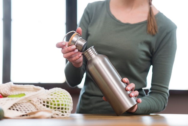 Foto gratuita thermos della bottiglia di apertura della donna del primo piano