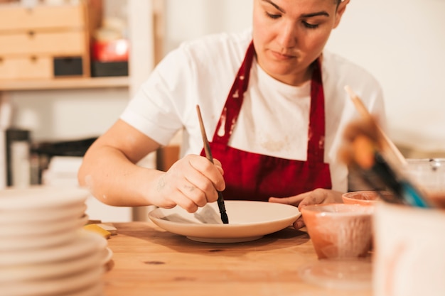 Close-up of woman painting ceramic figure with paintbrush