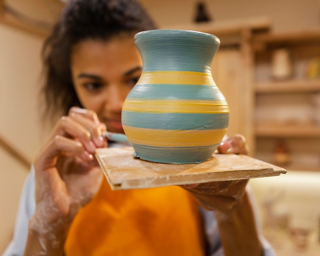 Free photo close up woman painting clay pot