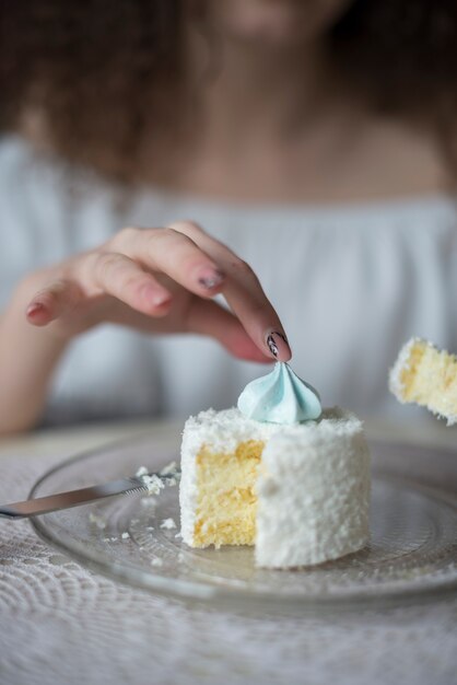 皿の上のケーキの上のメレンゲを拾う女性のクローズアップ