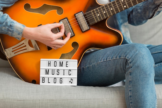 Close-up woman playing guitar at home