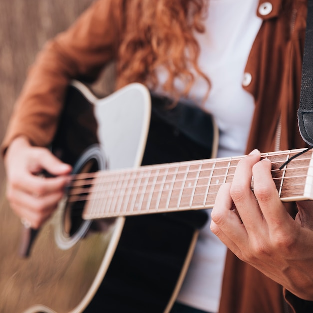 Close-up woman playing guitar