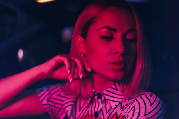 Close up woman portrait in red light touching her chin with hand in the dark